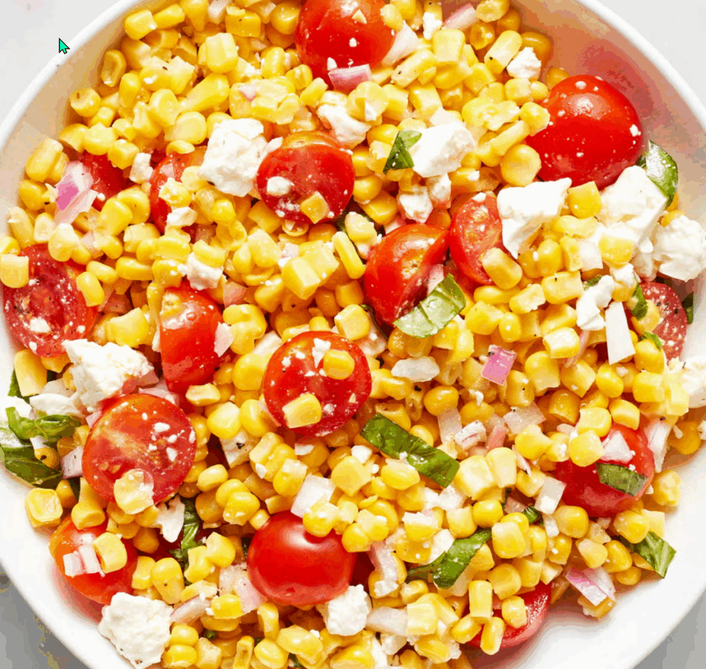 Summer corn salad with cherry tomatoes, feta cheese, and fresh herbs, ideal for picnics and BBQs.